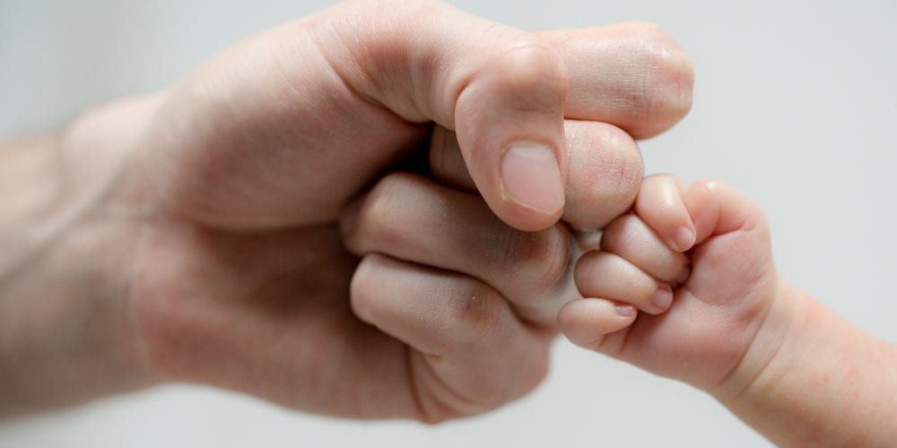 Dad and baby - Dad and baby touching knuckles symbolising dad and baby bonding