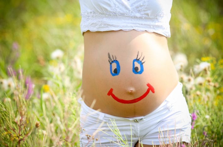 Pregnant woman in a good mood - happy face on stomach