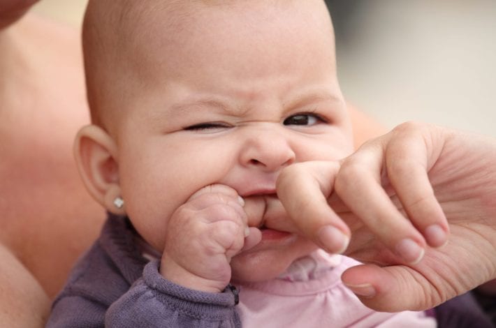 baby teething biting down on a finger