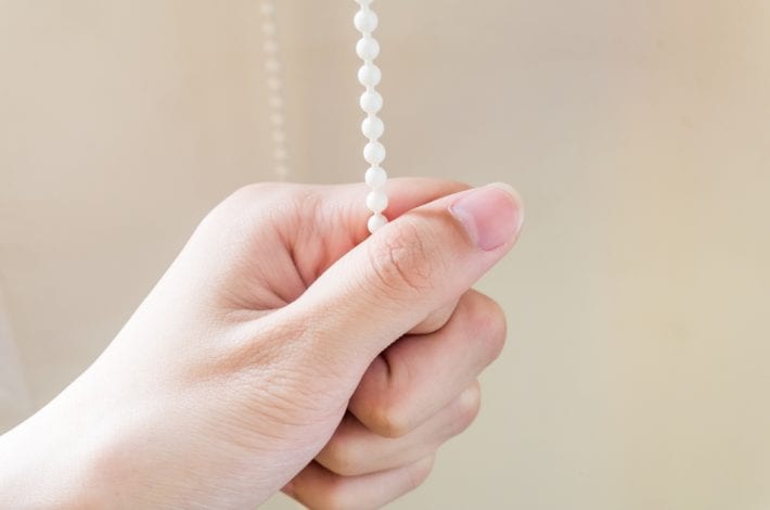 blind cord with hand showing danger of cords for toddlers